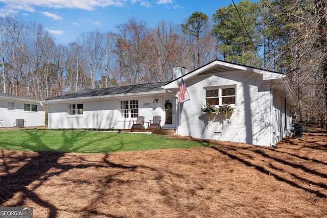 rear view of property with central AC, brick siding, crawl space, and a lawn