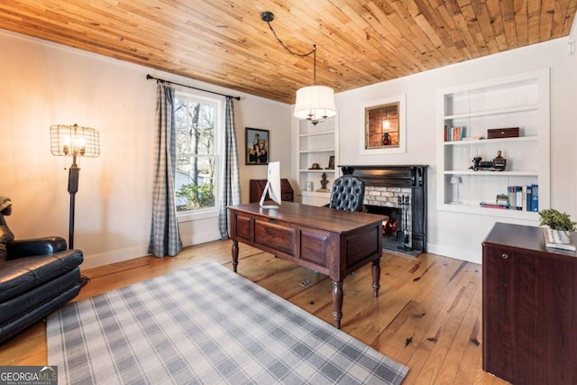 home office with built in shelves, hardwood / wood-style floors, a brick fireplace, wood ceiling, and baseboards