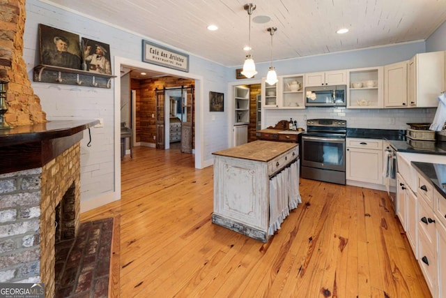 kitchen featuring open shelves, hanging light fixtures, appliances with stainless steel finishes, light wood-style floors, and a kitchen island