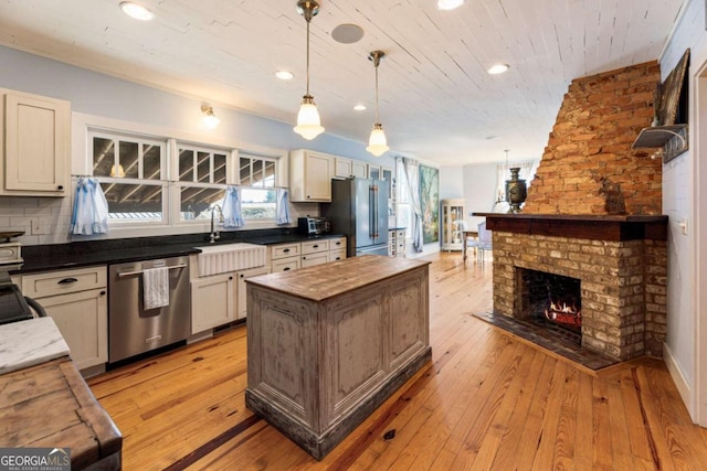 kitchen featuring light wood-type flooring, appliances with stainless steel finishes, a sink, and a center island