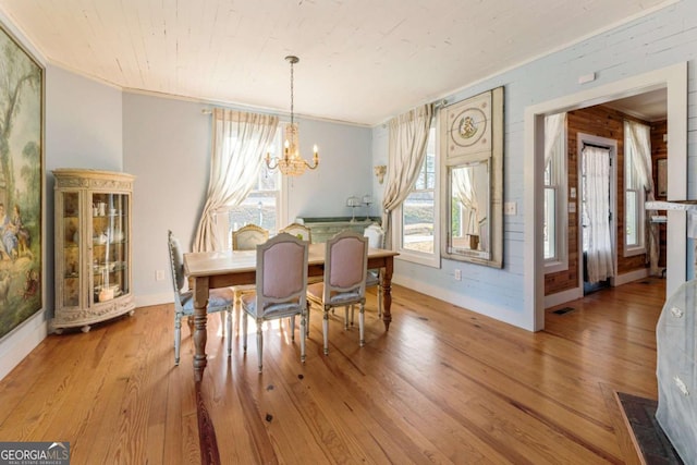 dining space featuring baseboards, crown molding, an inviting chandelier, and wood finished floors