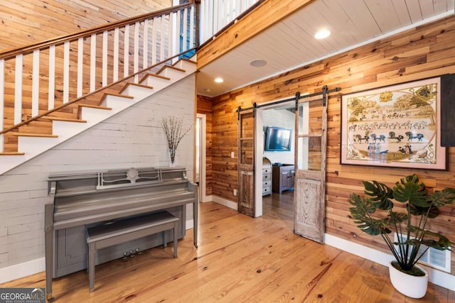 hallway featuring a barn door, wood walls, and wood finished floors