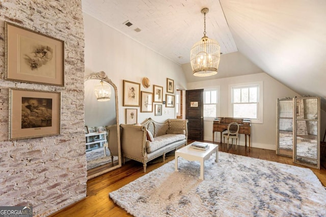 living area with visible vents, vaulted ceiling, wood finished floors, and a chandelier