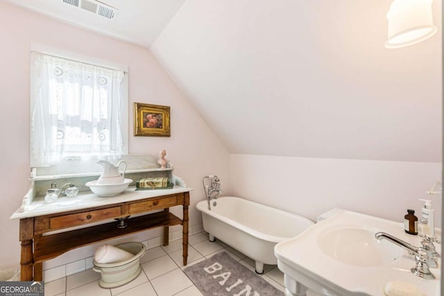 bathroom featuring lofted ceiling, a soaking tub, visible vents, vanity, and tile patterned floors