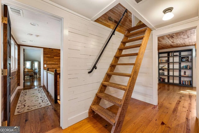 stairs featuring wood walls, wood ceiling, visible vents, and hardwood / wood-style flooring