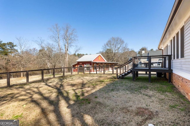 view of yard featuring a deck, fence, and stairway