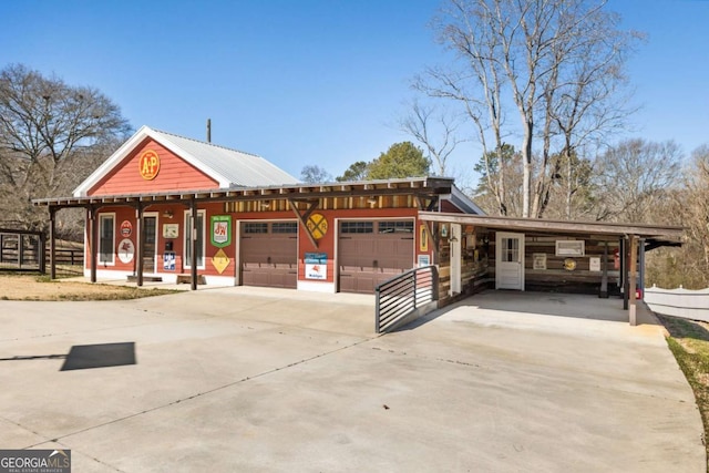 view of front facade featuring an attached garage, a carport, fence, and concrete driveway