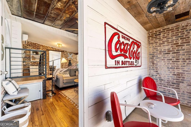 dining space featuring lofted ceiling, wooden ceiling, wooden walls, brick wall, and wood finished floors