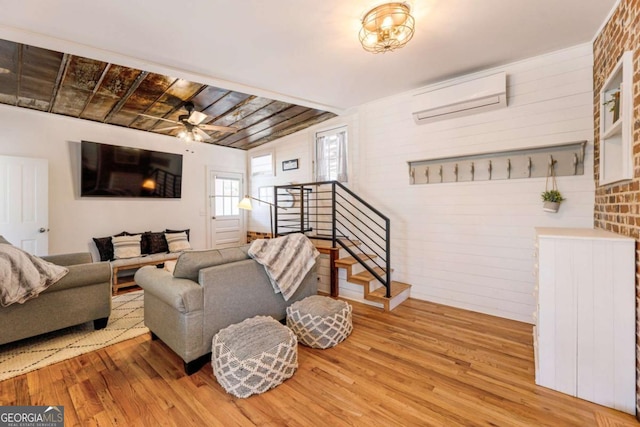 living area featuring stairs, ceiling fan, a wall mounted air conditioner, and wood finished floors