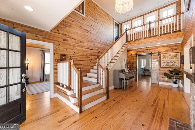 foyer featuring stairs, a barn door, and wooden walls