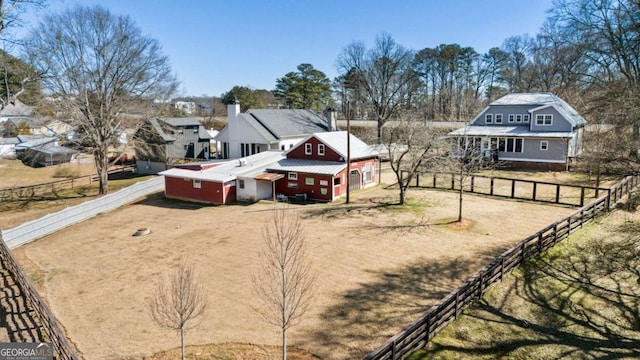 exterior space featuring a barn, dirt driveway, fence, and an outbuilding