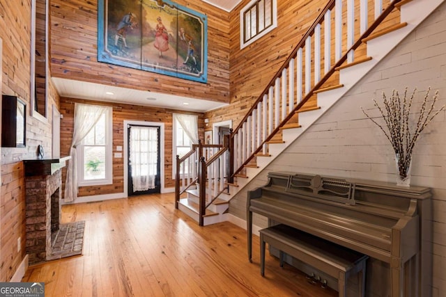 foyer entrance featuring stairway, wood-type flooring, a towering ceiling, and wooden walls