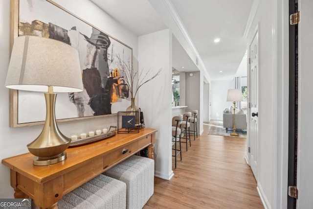 corridor with baseboards, ornamental molding, wood finished floors, and recessed lighting