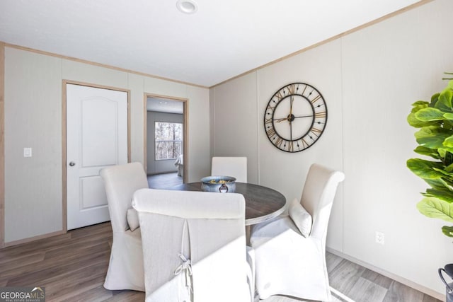 dining space featuring wood finished floors and crown molding