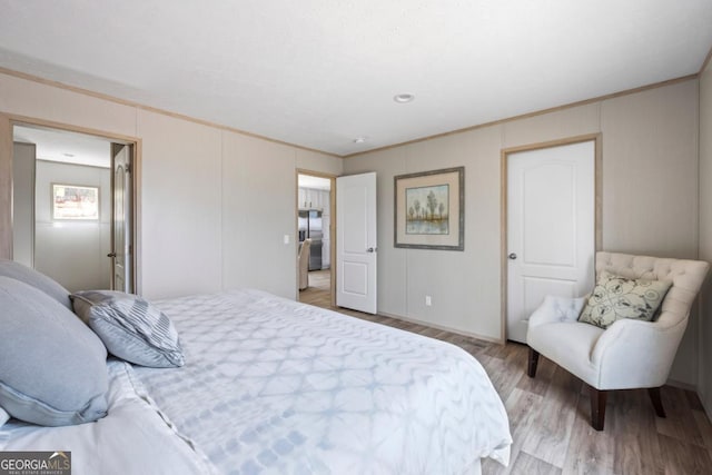 bedroom featuring stainless steel fridge with ice dispenser, wood finished floors, and crown molding