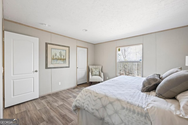 bedroom featuring ornamental molding, a textured ceiling, and wood finished floors