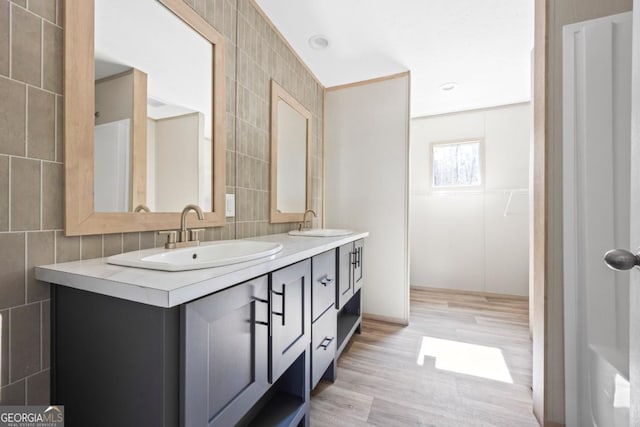 full bath with a sink, tile walls, and double vanity