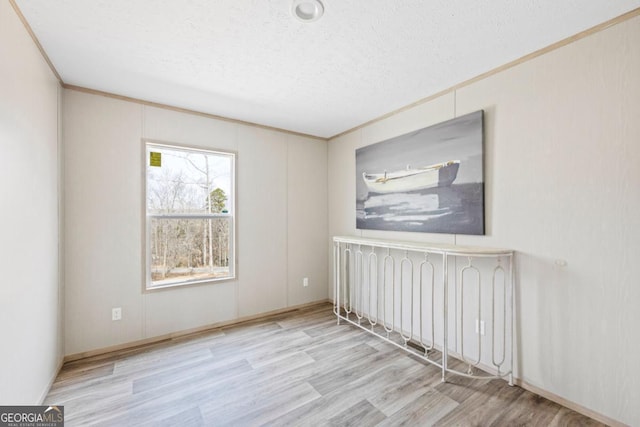 empty room with radiator, crown molding, a textured ceiling, and wood finished floors