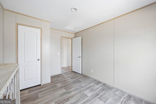 spare room featuring light wood-style floors and crown molding