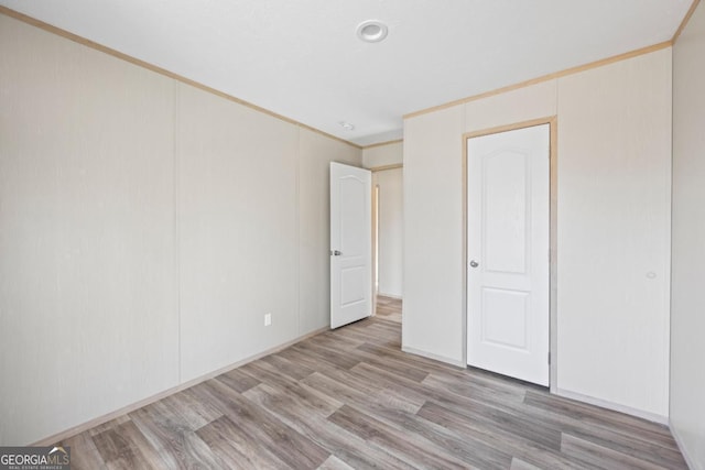 unfurnished bedroom featuring light wood finished floors and crown molding