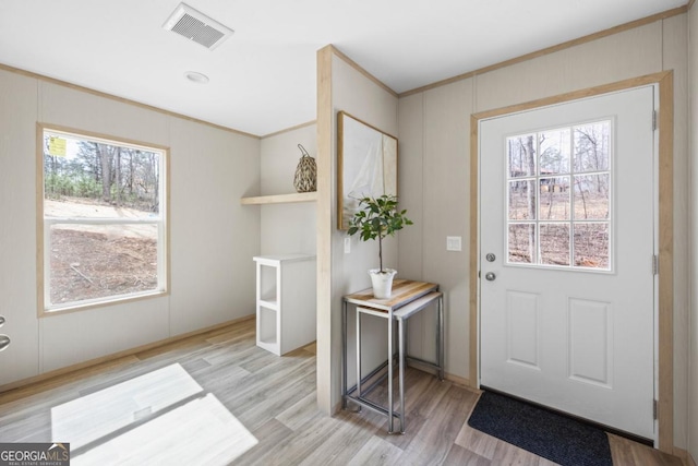 doorway featuring ornamental molding, light wood-type flooring, and visible vents