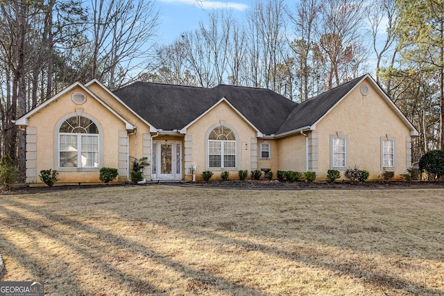 ranch-style house with roof with shingles, a front yard, and stucco siding