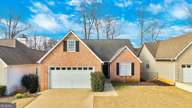 traditional-style home with driveway, an attached garage, a shingled roof, and brick siding