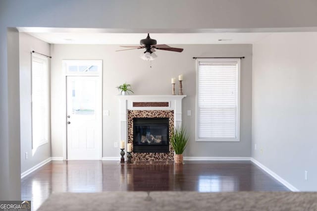 unfurnished living room featuring ceiling fan, baseboards, wood finished floors, and a tile fireplace