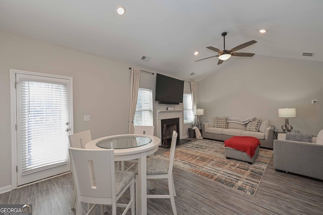 living area featuring lofted ceiling, a fireplace, wood finished floors, and visible vents