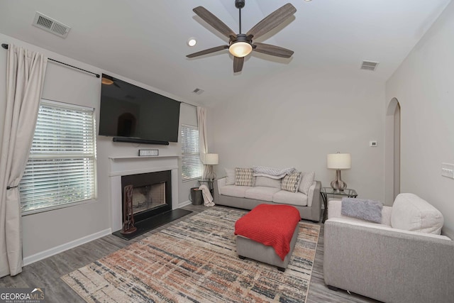 living area with lofted ceiling, plenty of natural light, visible vents, and wood finished floors