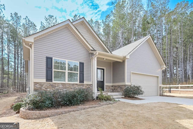 view of front of home featuring a garage, stone siding, fence, and concrete driveway