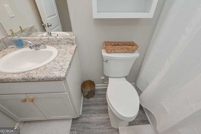 bathroom featuring baseboards, vanity, toilet, and wood finished floors