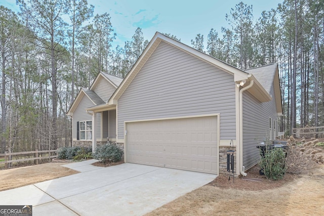 view of front of home featuring a garage, stone siding, fence, and driveway