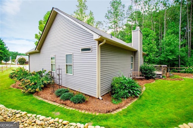 view of home's exterior featuring a chimney, a deck, and a lawn