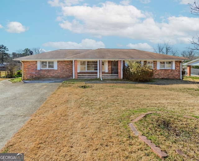 ranch-style house with driveway, brick siding, and a front yard