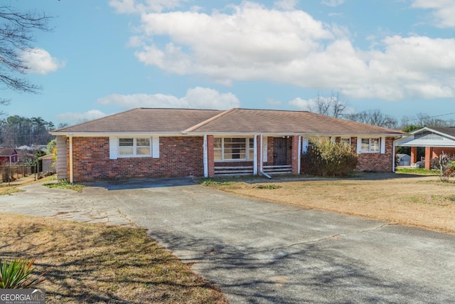 ranch-style home with brick siding, a front lawn, and aphalt driveway