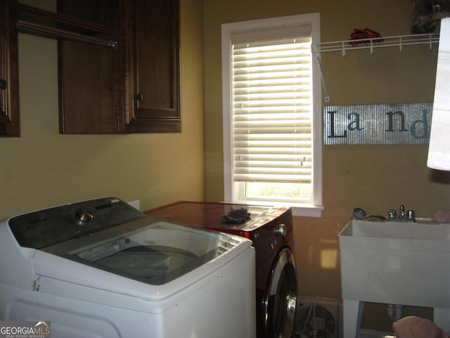 clothes washing area with cabinet space, independent washer and dryer, and a sink