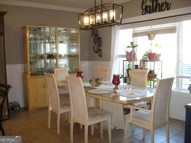 dining space featuring ornamental molding, a wainscoted wall, and light tile patterned floors