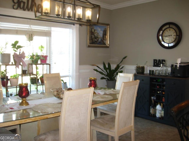 dining room featuring ornamental molding, a wainscoted wall, and tile patterned floors