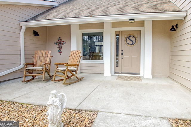 doorway to property featuring a porch and roof with shingles