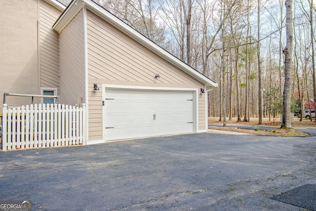 garage featuring aphalt driveway and fence