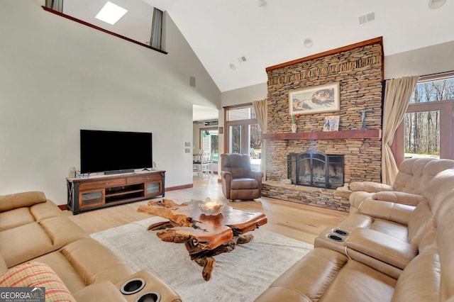 living room featuring high vaulted ceiling, visible vents, a fireplace, and wood finished floors