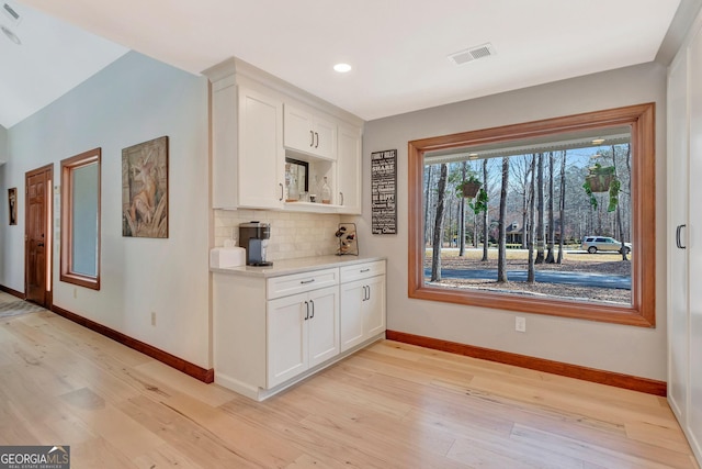 interior space with tasteful backsplash, recessed lighting, visible vents, light wood-style flooring, and baseboards