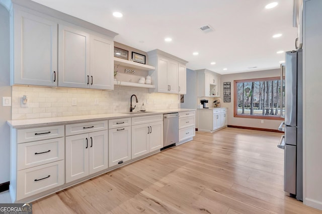 kitchen featuring tasteful backsplash, white cabinets, appliances with stainless steel finishes, open shelves, and a sink