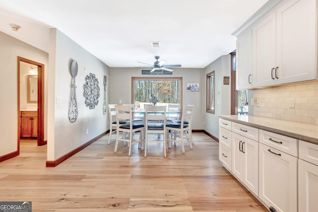 dining space with light wood finished floors, ceiling fan, visible vents, and baseboards