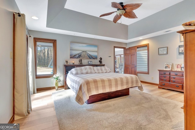 bedroom featuring baseboards, a raised ceiling, visible vents, and light wood-style floors