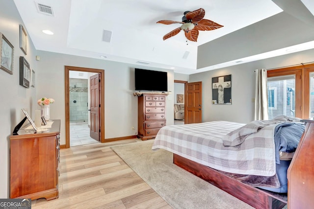 bedroom with ceiling fan, visible vents, baseboards, light wood-type flooring, and a tray ceiling