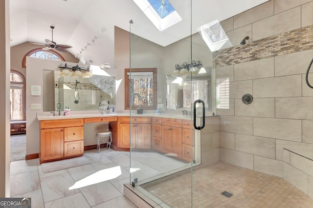 bathroom with double vanity, lofted ceiling with skylight, a stall shower, and a sink