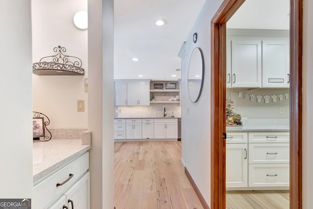 kitchen with light stone counters, white cabinets, backsplash, open shelves, and light wood finished floors