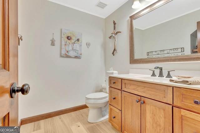 bathroom with crown molding, visible vents, toilet, vanity, and wood finished floors